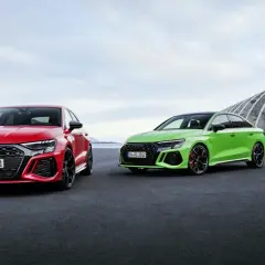 Dwa Audi RS 3 Sportback: czerwone i zielone, zaparkowane na zewnątrz.