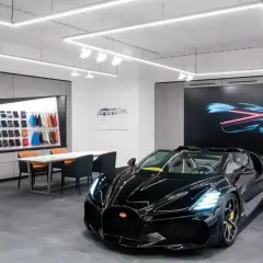 Czarny Bugatti w salonie, obok próbek skór i ekranu z grafiką. Ile jest Bugatti w Polsce? Trudno powiedzieć, ale ten wygląda na pierwszy.