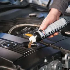 Dłoń wlewa płyn spulung liqui moly do silnika samochodu.
