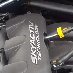 Silnik SKYACTIV TECHNOLOGY, jeden z najlepszych silników benzynowych, z widocznymi przewodami i złączkami.