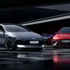 Dwa modele Hyundai Ioniq 6, jeden szary, drugi czerwony, stoją na mokrej nawierzchni w nowoczesnym wnętrzu.