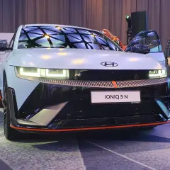 Hyundai IONIQ 5 N na prezentacji, z otwartymi drzwiami, w tle ludzie i logo Hyundai.