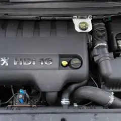 Silnik Peugeot 307 2.0 HDi 16V. Widoczny czarny plastikowy kolektor, zbiorniczek płynu hamulcowego i elementy układu dolotowego.