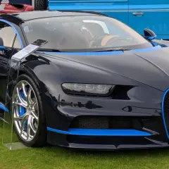 Ciemnoniebieskie Bugatti Chiron z niebieskimi akcentami na trawie.
