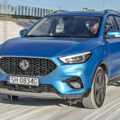 Niebieski MG ZS Classic jedzie po zaśnieżonej drodze. Kierowca w okularach prowadzi auto.