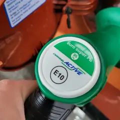 Dłoń trzyma zielony pistolet dystrybutora paliwa z oznaczeniami 95 Pb i E10.