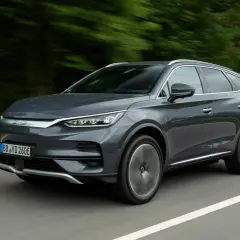 Szary SUV BYD Tang w ruchu drogowym, z rozmytym tłem drzew.