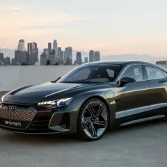 Elegancki Audi e-tron GT na tle miejskiej panoramy o zachodzie słońca.