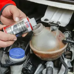Ręce wlewają Liqui Moly Uszczelniacz chłodnicy do zbiorniczka wyrównawczego.