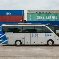 Autobus nauki jazdy "Linia" na tle kontenerów. Oferują kursy na prawo jazdy kategorii AM, A, B1, B, B+E, C, C+E, D1, D.