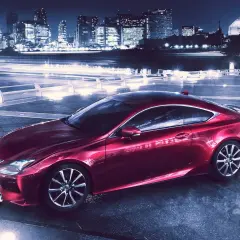 Czerwony Lexus RC 350 na tle nocnego miasta z rozmazanymi światłami.