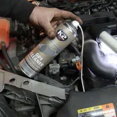 Ręka trzyma puszkę płynu do wypalania DPF, który pomaga oczyścić filtr cząstek stałych w silniku.
