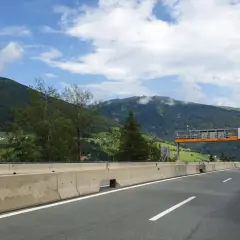 Autostrada w Austrii z widokiem na góry, znaki drogowe i ciężarówka.