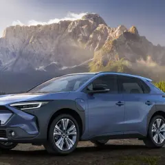 Niebieski Subaru Solterra na tle gór i jeziora.