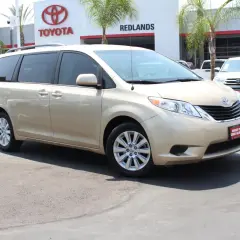Złoty minivan Toyota Sienna zaparkowany przed salonem Toyoty.