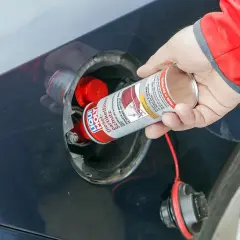 Ręka wlewa dodatek do diesla DPF do baku samochodu. Preparat chroni filtr cząstek stałych.