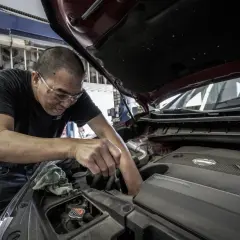 Mechanik pracuje przy silniku, sprawdzając, ile kosztuje wymiana oleju z filtrami.