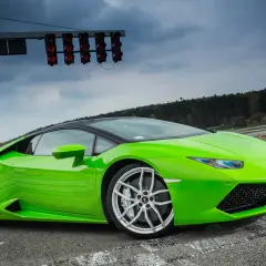 Zielony Lamborghini Huracan na torze wyścigowym, gotowy do startu pod światłami.