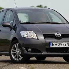 Szary samochód Toyota Auris na drodze, przód auta z bliska.