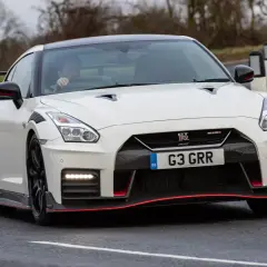 Biały Nissan GT-R Nismo z czerwonymi akcentami pędzi po drodze.