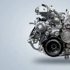 Złożony silnik wysokoprężny, znany jako diesel, z licznymi paskami i kołami pasowymi.