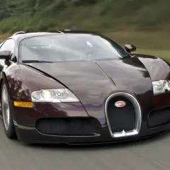Ciemnobrązowy Bugatti Veyron pędzi po drodze. Ten hipersamochód ma 16 cylindrów, co przekłada się na jego niesamowitą moc.