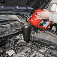 Wlewanie oleju ATF do skrzyni biegów. Czerwony kanister z płynem.