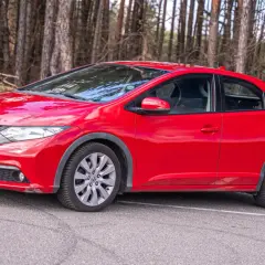 Czerwony Honda Civic IX na tle lasu.