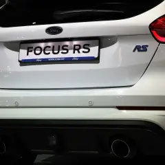 Tył białego Forda Focus RS z widocznymi światłami, napisem "FOCUS RS" i podwójnymi końcówkami wydechu.