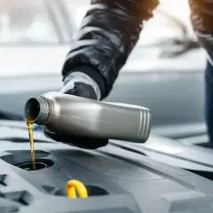 Ręka w rękawiczce wlewa olej do silnika. To może być odpowiedni dodatek do diesla common rail, dbający o jego żywotność.