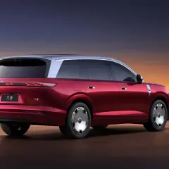 Czerwony elektryczny SUV BYD Tang z dwukolorowym nadwoziem na tle zachodzącego słońca.