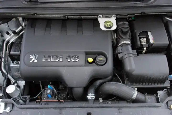 Silnik Peugeot 307 2.0 HDi 16V. Widoczny czarny plastikowy kolektor, zbiorniczek płynu hamulcowego i elementy układu dolotowego.