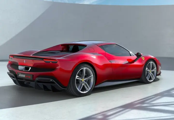 Czerwone Ferrari 296 GTB widziane z tyłu, na tle białej ściany i nieba.