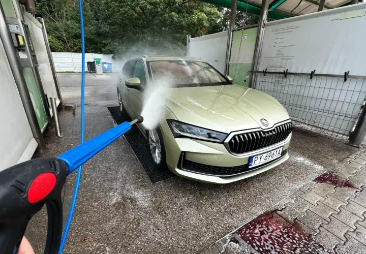 Mycie samochodu na myjni bezdotykowej. Woda pod ciśnieniem spływa po masce, pomagając zmyć żywicę z samochodu.