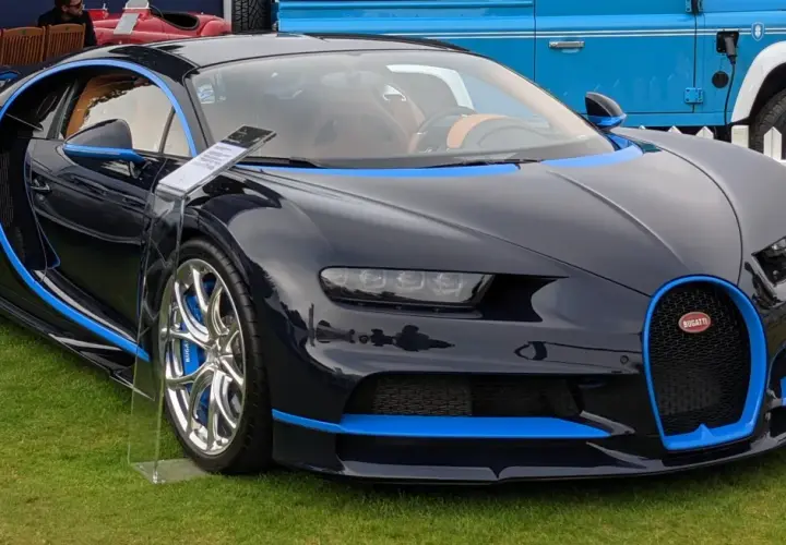 Ciemnoniebieskie Bugatti Chiron z niebieskimi akcentami na trawie.