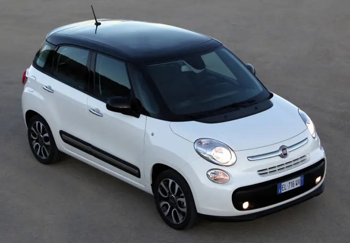 Biały Fiat 500 L z czarnym dachem, zaparkowany na szarym podłożu.
