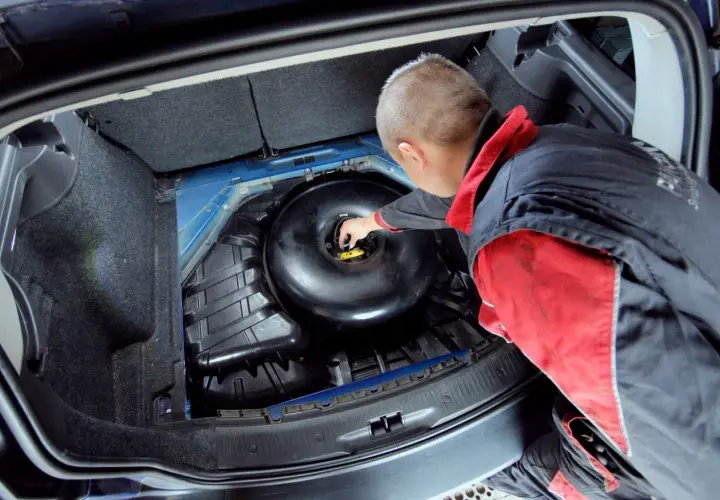 Mechanik sprawdza butlę LPG w bagażniku. Dowiedz się, ile kosztuje legalizacja butli LPG i jakie są wymagania.