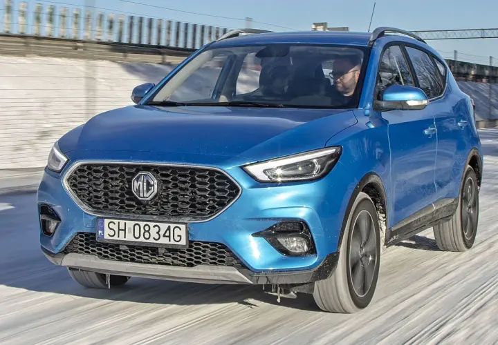 Niebieski MG ZS Classic jedzie po zaśnieżonej drodze. Kierowca w okularach prowadzi auto.