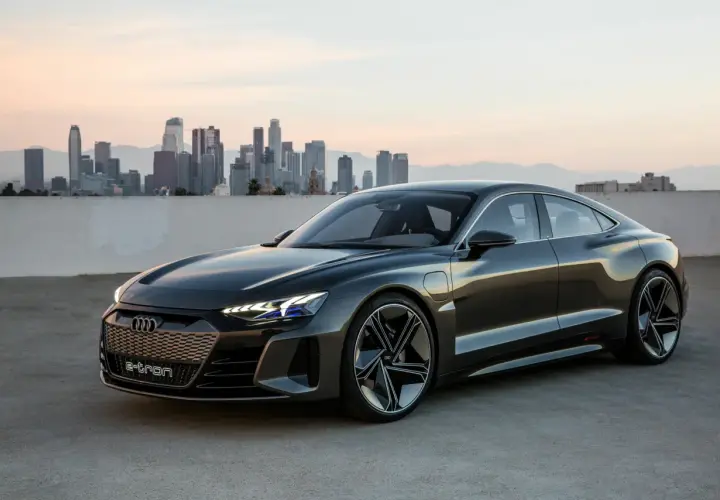 Elegancki Audi e-tron GT na tle miejskiej panoramy o zachodzie słońca.