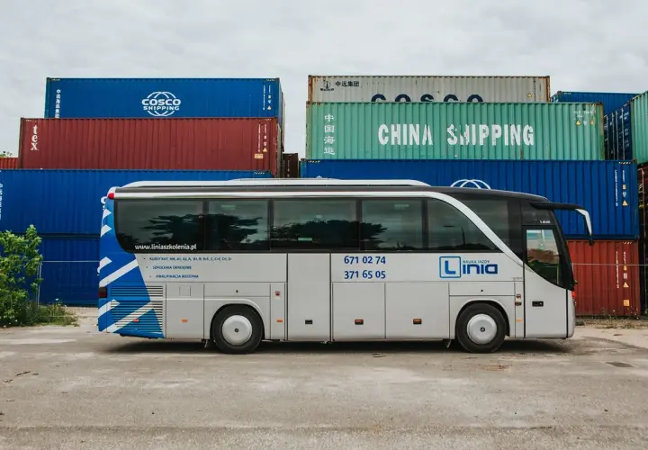 Autobus nauki jazdy "Linia" na tle kontenerów. Oferują kursy na prawo jazdy kategorii AM, A, B1, B, B+E, C, C+E, D1, D.