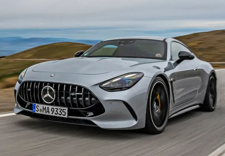 Srebrny Mercedes-AMG GT sunie po krętej drodze, ukazując swoją sportową sylwetkę i potężny grill.