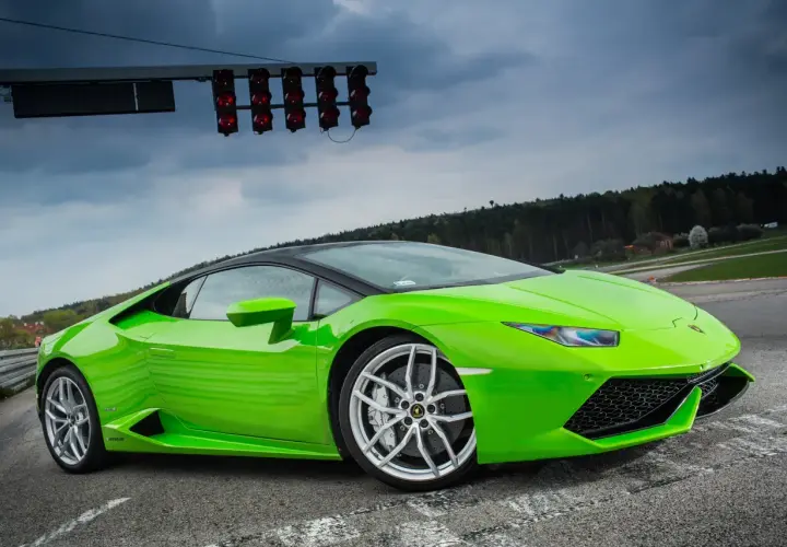 Zielony Lamborghini Huracan na torze wyścigowym, gotowy do startu pod światłami.