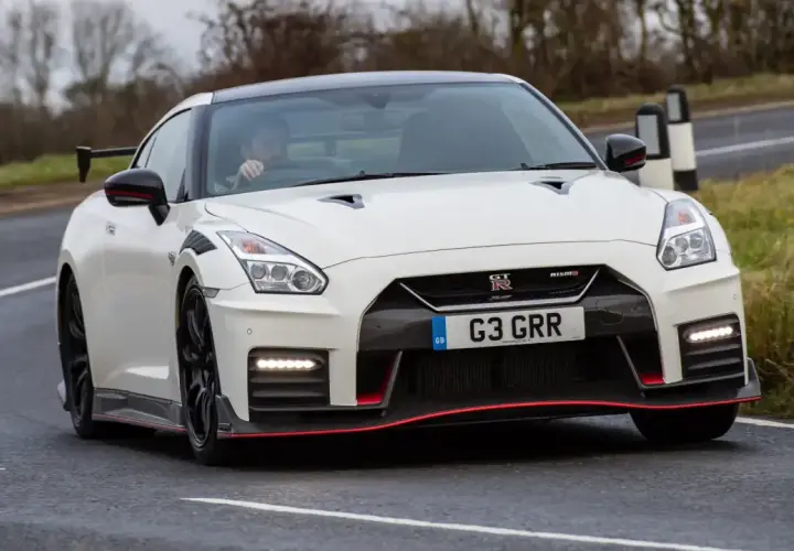 Biały Nissan GT-R Nismo z czerwonymi akcentami pędzi po drodze.