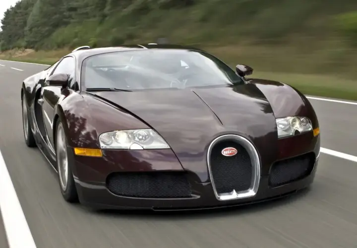 Ciemnobrązowy Bugatti Veyron pędzi po drodze. Ten hipersamochód ma 16 cylindrów, co przekłada się na jego niesamowitą moc.