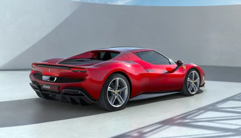 Czerwone Ferrari 296 GTB widziane z tyłu, na tle białej ściany i nieba.