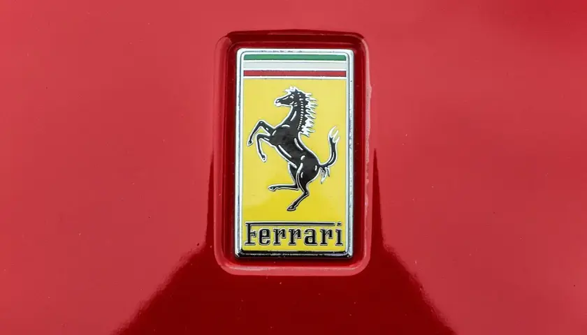 Jaki znaczek ma Ferrari? Czarny koń na żółtym tle, z napisem Ferrari.