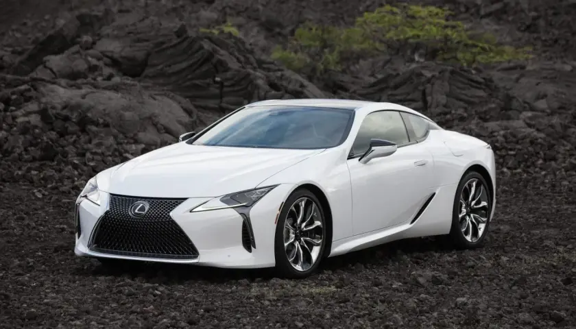 Biały Lexus LC 500 na tle wulkanicznych skał.