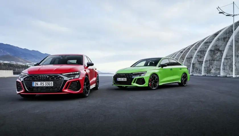 Dwa Audi RS 3 Sportback: czerwone i zielone, zaparkowane na zewnątrz.