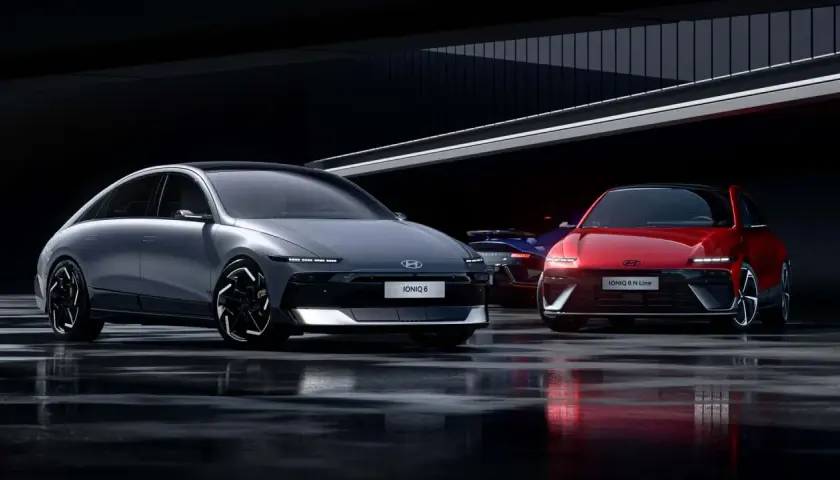 Dwa modele Hyundai Ioniq 6, jeden szary, drugi czerwony, stoją na mokrej nawierzchni w nowoczesnym wnętrzu.