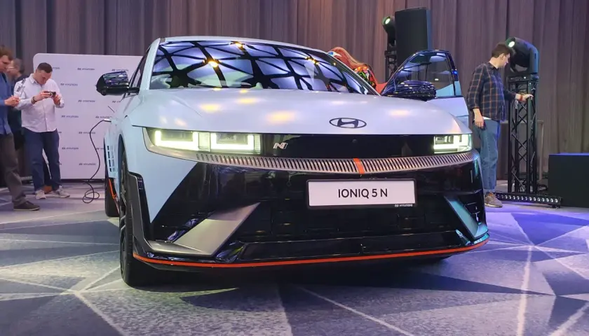 Hyundai IONIQ 5 N na prezentacji, z otwartymi drzwiami, w tle ludzie i logo Hyundai.